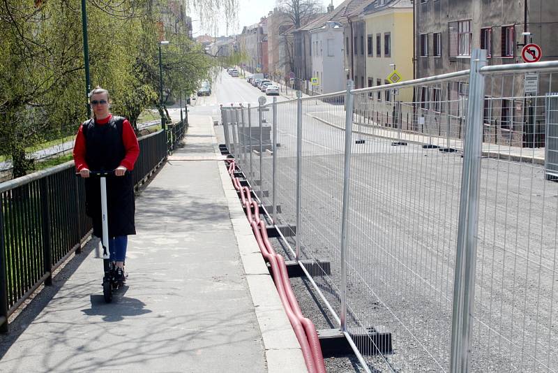 Na uzavřeném železničním nadjezdu v Nymburce dělníci s pomocí těžké techniky pracují na odstranění stávajících chodníků.