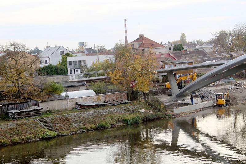 Práce na konci října roku 2021 na stavbě nové lávky přes řeku Labe v Nymburce: úpravy povrchu na samotné lávce, dodělávání příjezdových cest, dláždění přímo pod lávkou na březích.