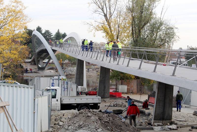 Práce na konci října roku 2021 na stavbě nové lávky přes řeku Labe v Nymburce: úpravy povrchu na samotné lávce, dodělávání příjezdových cest, dláždění přímo pod lávkou na březích.