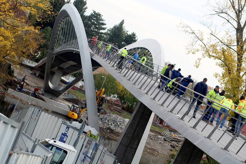 Práce na konci října roku 2021 na stavbě nové lávky přes řeku Labe v Nymburce: úpravy povrchu na samotné lávce, dodělávání příjezdových cest, dláždění přímo pod lávkou na březích.