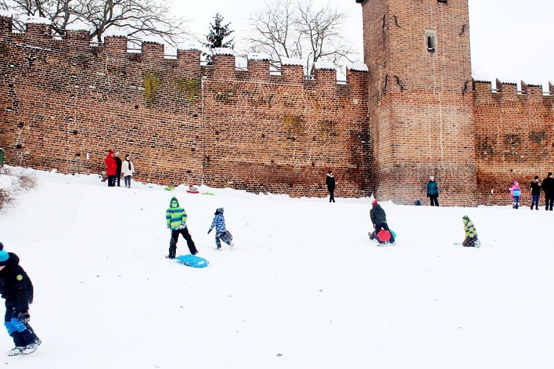 Děti si užívají sníh na několika kopečcích v Nymburce.