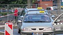 Taxi čekající na zákazníky na rozkopaném přednádraží 