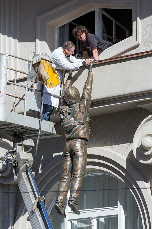 Instalace sochy Davida Černého na římse Muzea umění v Olomouci. Autor v okně