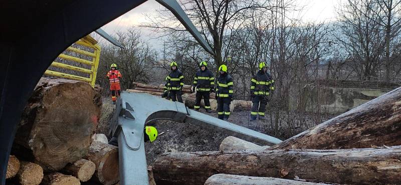 Hasiči rozřezávali motorovými pilami velké kusy dřeva a odklízeli z trati v železniční stanici v Prosenicích, kde došlo k vykolejení vlaků. 14. ledna 2022