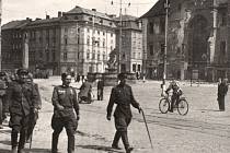 Květen 1945. Sovětští vojáci pochodují po Horním náměstí v Olomouci u poničené radnice. Orloj poškodily události války, byl přebudován v letech 1947-1955.