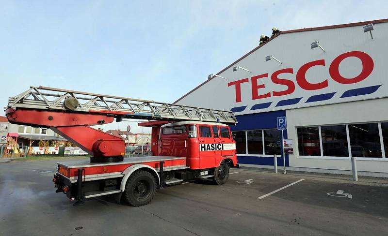 Hasiči připevňují uvolněnou střechu na supermarketu v Litovli