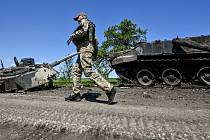 Ukrajinský voják míjí zničený ruský tank v Záporožské oblasti