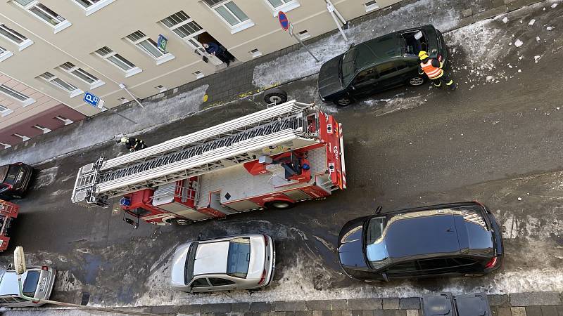 Sněhové převisy ze střech a rampouchy na římsách ohrožují chodce i zaparkovaná auta. Na snímku zásah hasičů ve Vančurově ulici v Olomouci, kde sjel zmrzlý sníh ze střechy a poškodil auto, 18. února 2021