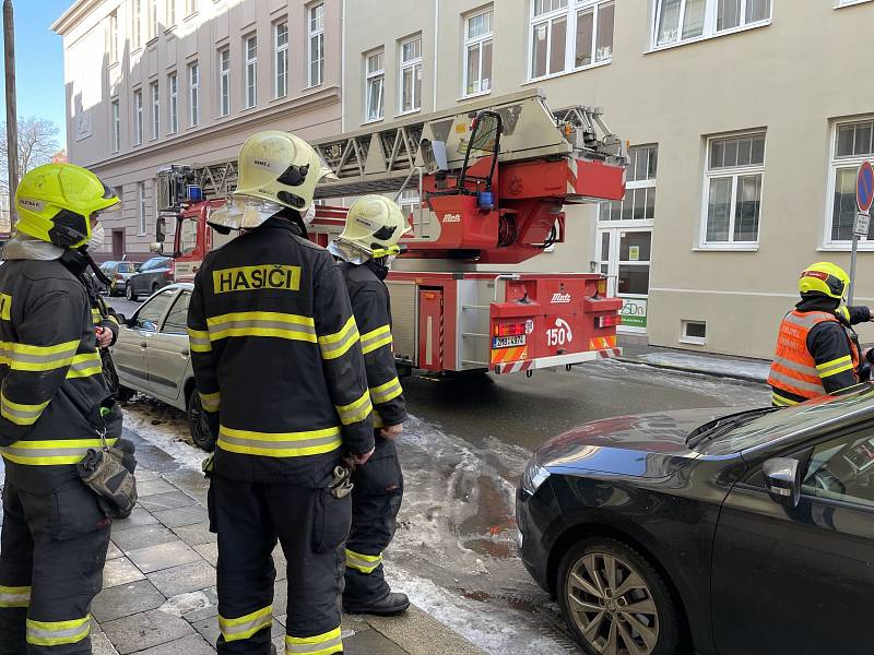 Sněhové převisy ze střech a rampouchy na římsách ohrožují chodce i zaparkovaná auta. Na snímku zásah hasičů ve Vančurově ulici v Olomouci, kde sjel zmrzlý sníh ze střechy a poškodil auto, 18. února 2021