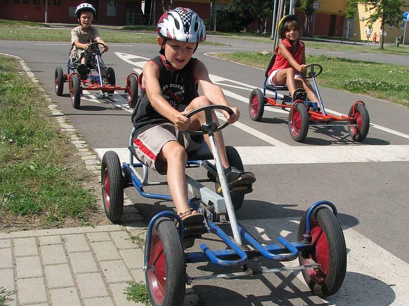 Děti právě projíždějí křižovatkou na dopravním hřišti 