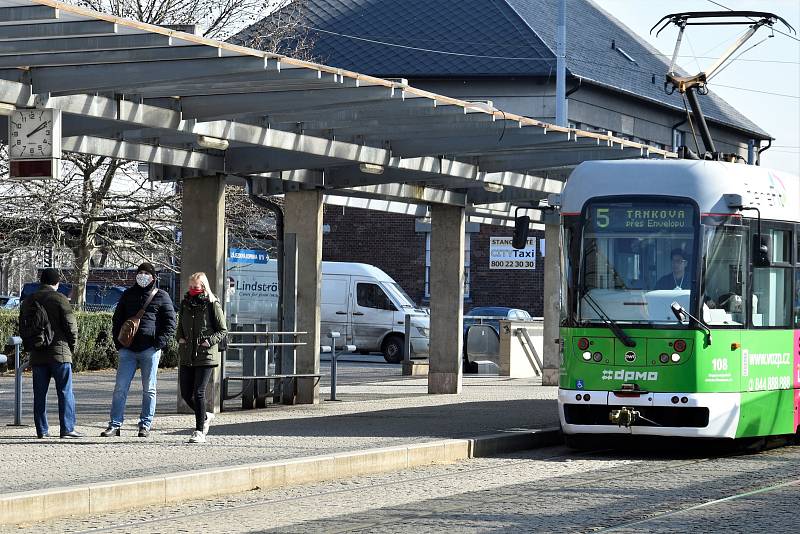 Řidič tramvaje zastavuje, zakrývá si obličej a teprve potom vpouší cestující dovnitř. Po dobu jízdy už roušku nesundá