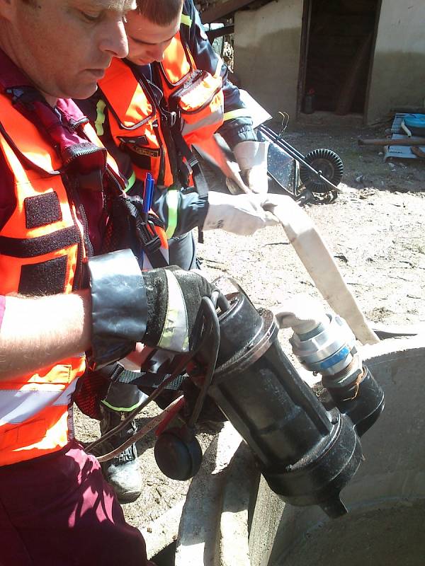Dobrovolní hasiči z Lázní Bohdaneč pomáhají čistit studnu.