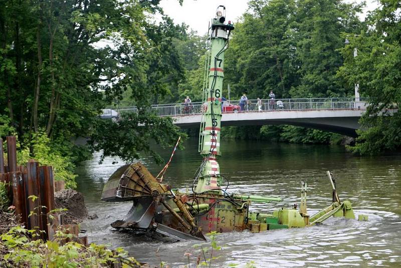 Dálkově ovládaný bagr čistí dno řeky od nánosů bahna