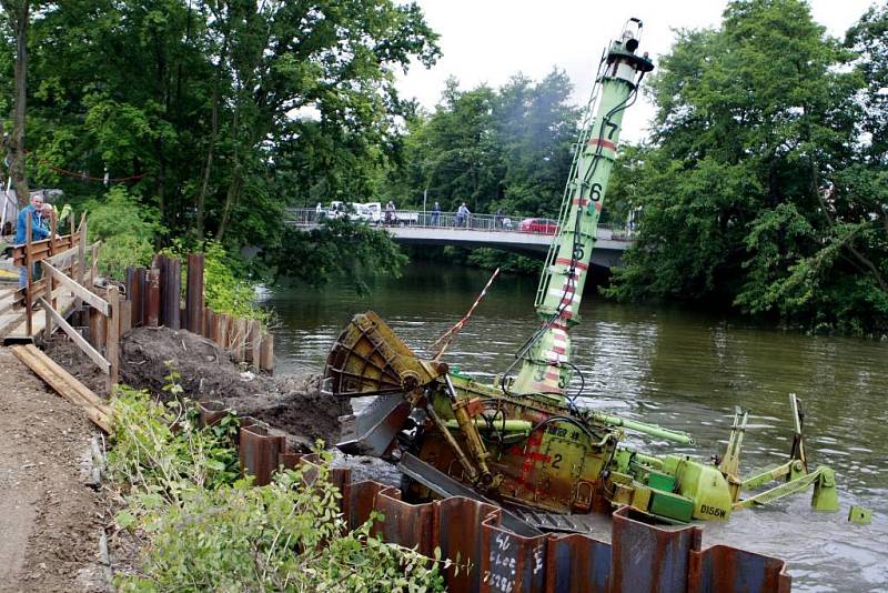 Dálkově ovládaný bagr čistí dno řeky od nánosů bahna