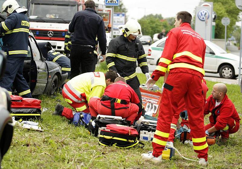 Záchranáři na místě resuscitují posádku osobního vozidla. Řidiči zaklíněnému v kabině už nebylo pomoci.