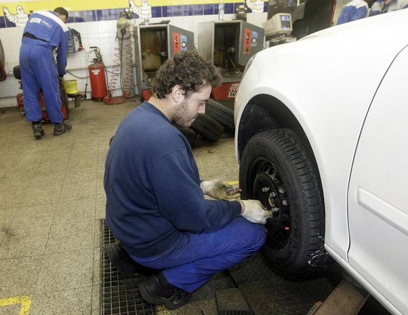 Pracovníci pneuservisu při 'přezouvání' automobilu.