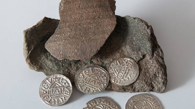 Nalezené mince z 10. století, kdy vládl Boleslav II. spolu s fragmenty nádoby, ve které byly uloženy do země.
