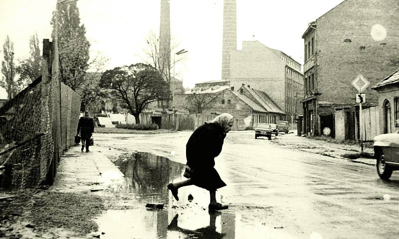 ROK 1970: pohled na křižovatku Karlovy ulice (se stromy tzv. parečku), která tehdy pokračovala až k dnešní „myší díře“ na konci Sladkovského ulice (ulice vedoucí na snímku vpravo) a ulice Anenské (vedoucí za ohradu vlevo). Vidíme též dva komíny elektrárny