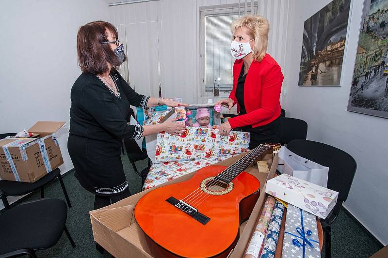 Na snímku členka iniciativy Holky holkám, ředitelka Nadace 700 let města Plzně Alena Kozáková (v červeném) a její kolegyně Lenka Bílá během balení dárků, které brzy zamíří do domovů.