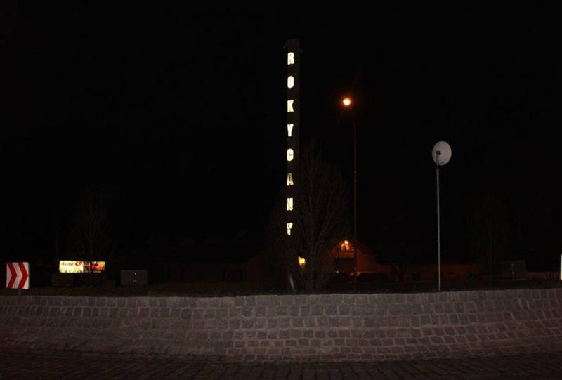 Rokycany. Řidiče, kteří vjíždějí do Rokycan ve směru od dálnice, vítá mohutný pylon, na němž do tmy svítí název města.