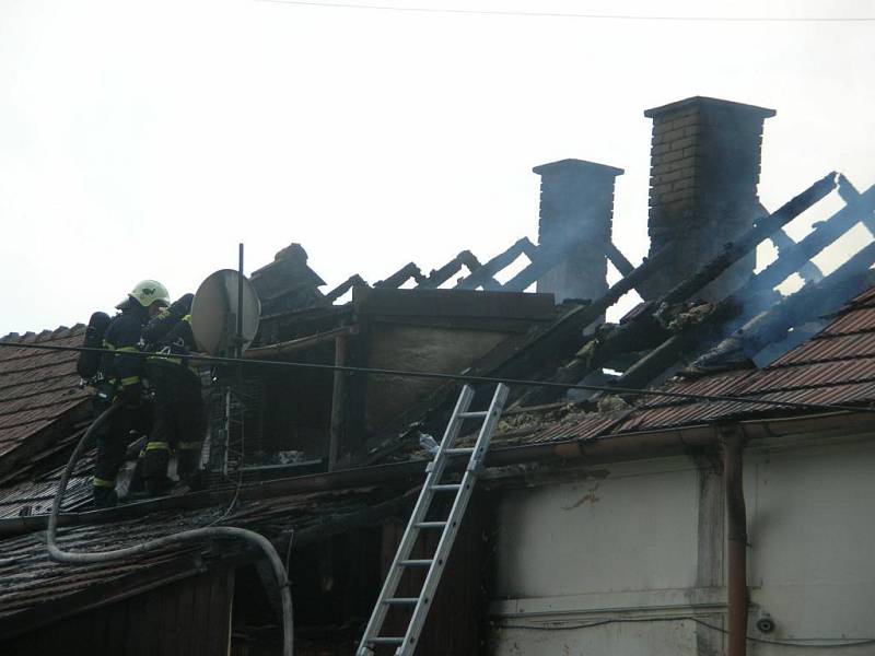 Hasiči rozebírají střechu a hasí zbytky požáru