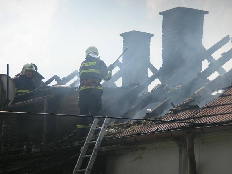 Hasiči rozebírají střechu a hasí zbytky požáru