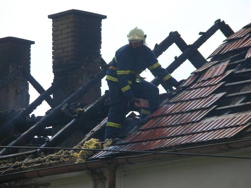 Hasiči rozebírají střechu a hasí zbytky požáru