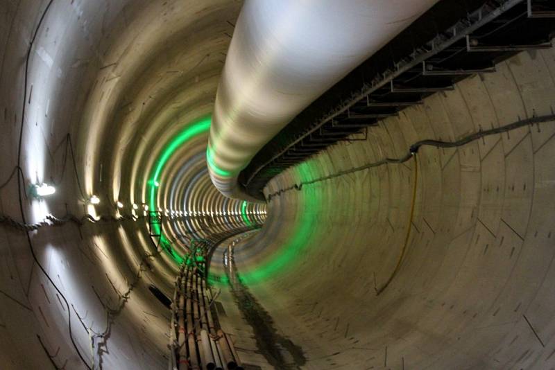 Tubus pod stropem tunelu, který stavbařům od ústí až k razicímu štítu přivádí vzduch, a vedle něj pásového dopravníku, který naopak od razicího štítu ven z tunelu vyváží vytěženou zem