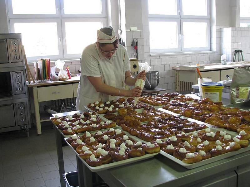 Vdolky, vdolky, vdolky. Zdobení nebere konce. Namazat, vyskládat, stříknout šlehačkou. Jo, 180 strávníků má holt hlad, takže se kuchařky musí otáčet