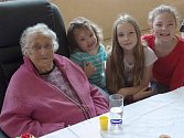 Stoletá Růžena Sinkulová se třemi prapravnučkami, vpravo dole pak její vítaní narozeninoví hosté