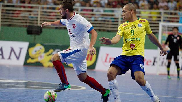 Futsalista Interobalu Tomáš Vnuk (v bílém dresu) byl jediným hráčem třetího celku VARTA futsal ligy na turnaji v Brazílii. Na snímku uniká domácímu reprezentantovi.