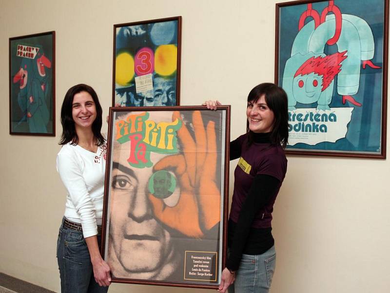 Pracovnice Espritu Václava Sporková (vlevo) a Tereza Štichová ukazují plakát k filmu Piti piti pa, který je společně s dalšími díly Karla Vaci vystaven v Besedě