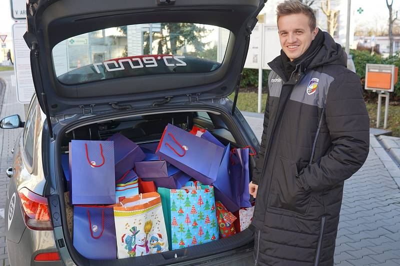 JAN KOPIC s kufrem auta plným vánočních dárků, které přinesli lidé pod stromeček u klubového fanshopu. Před odjezdem do Karviné tam zašli i jeho spoluhráči.