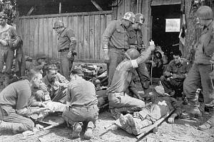 Zdravotníci americké 30. pěší divize ošetřují zraněné při útoku na Mortain v srpnu 1944