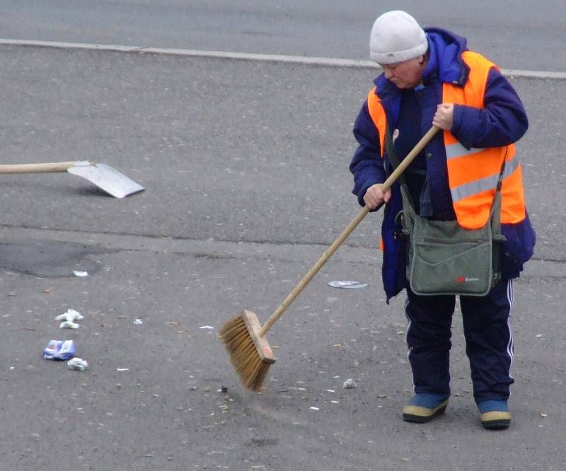 Zaměstnankyně technických služeb uklízí nepořádek v JIrsákových sadech po řidičích, kteří jednoduše vysypou obsah popelníků na zem.