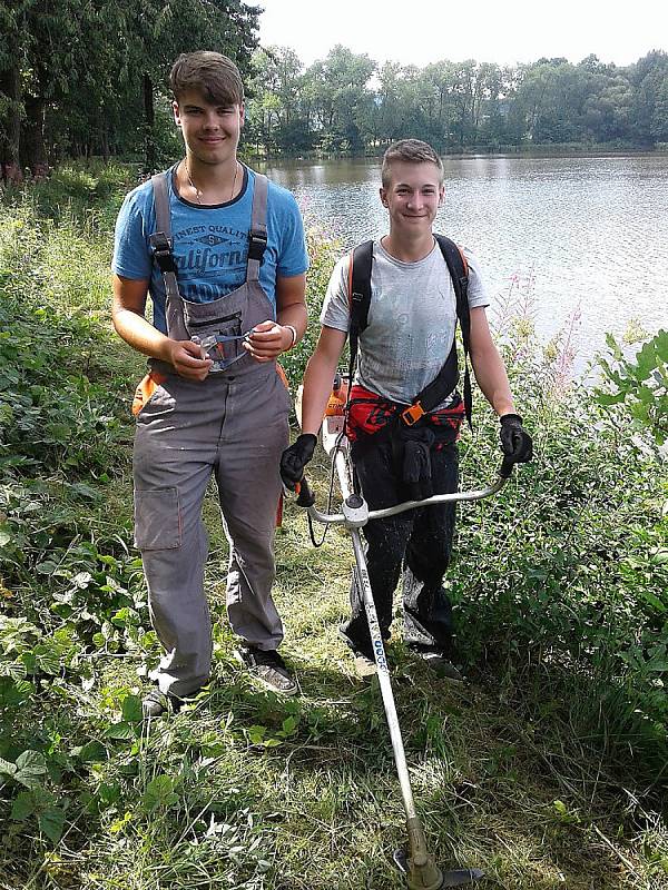 Děti z rybářského kroužku v Rožmitále při prázdninové údržbě břehu.