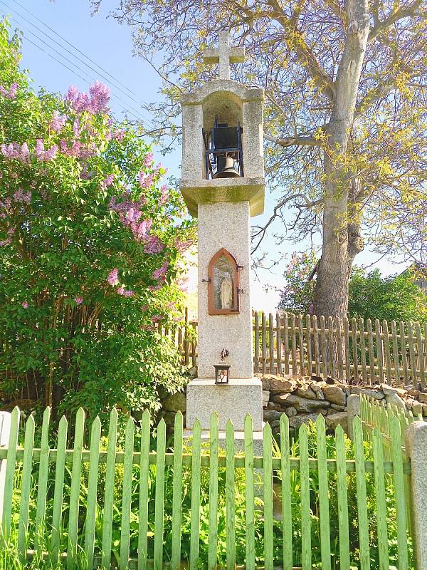 Z kamene tesaná zvonička z roku 1905 ve Veletíně, v jejíž přední části je zašpičatělý výklenek se soškou.