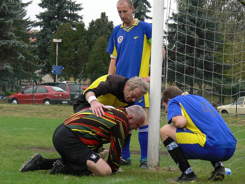 Kapitán týmu David Beneš, Gajdoš (vpravo) a rozhodčí Kodl se sklánějí nad veteránem v brance Františkem Pavlem, který schytal v Černém Dubu při utkání III. třídy hodně ran, porážce Trhových Svinů B 1:3 ale nezabránil. 