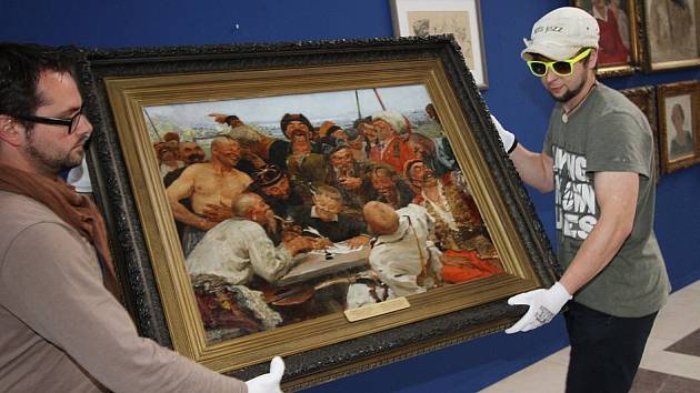 Alšova jihočeská galerie otevřela na Hluboké výstavu Ilja Repin a ruské umění. Nabízí přes 100 prací, potrvá do 27. září. Na snímku zaměstnanci galerie s dílem Ilji Repina Záporožští kozáci píší dopis tureckému sultánovi.
