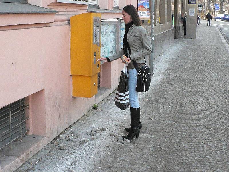 Rozbitá dlažba na zastávce MHD v ulici Na Sadech nutí zájemce o koupi jízdenky k hodně opatrnému našlapování. 