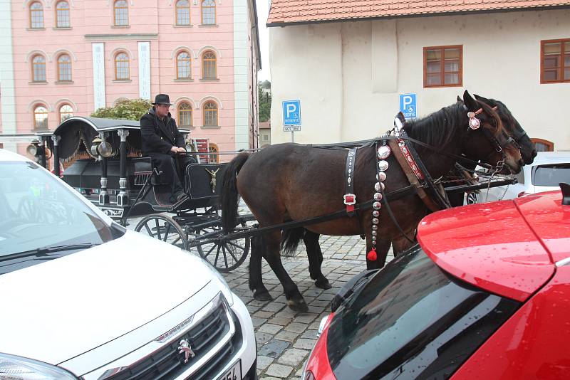 Pohřební kočár s dvěma koňmi projíždí centrem města.