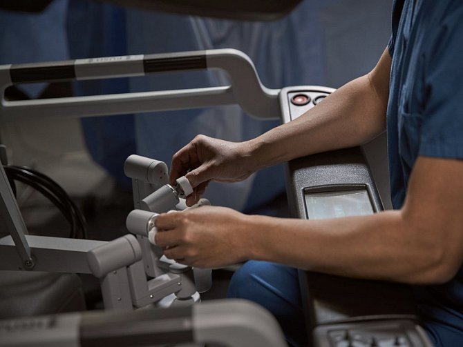 Chirurgická konzole (na snímku) – zde sedí chirurg, který ovládá na dálku pomocí speciálních prstových ovladačů tři robotické nástroje a endoskopickou kameru.