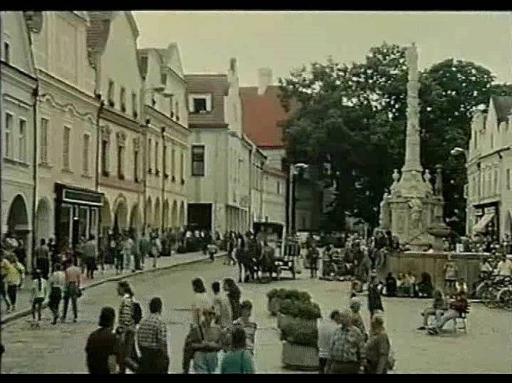 Záběr z filmu Divoké pivo. Třeboňské náměstí a na něm spousta lidí, přirození komparzisté. Na snímku je kašna a za ní morový sloup. Zajímavé je, že kolem kašny nejsou tři schůdky, které jsou tam dnes.