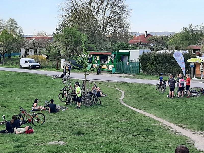 Občerstvení u Velkého jezu v Budějovicích má venkovní posezení předpisově uzavřené. Oblíbené místo svých procházek i cyklovyjížděk si Budějovičtí ale chtějí užít, a tak posedávají a postávají v okolí stánku na trávě u řeky. V malých skupinkách a rozestupe