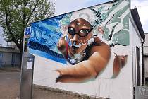Závodní plavkyně se vynořuje pod rukama místního streetartového umělce Dobse u budějovického bazénu.