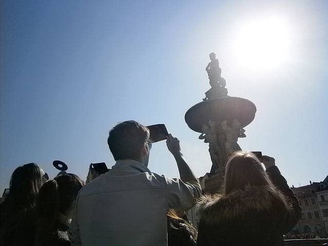 Lidé pozorují zatmění Slunce na českobudějovickém náměstí.
