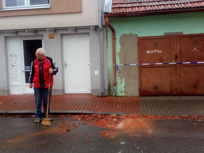 Muž před domem uklízel rozbité tašky ze střechy v Českých Budějovicích v Baarově ulici.