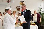Michal Malát z Asociace školních jídelen předává certifikát o kurzu kuchařkám z Jídelny U Tří lvů.