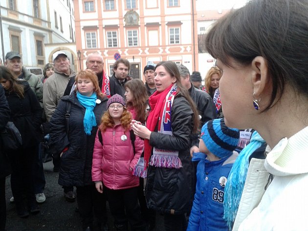 Účastníkům zájezdu udílí na Hradčanském náměstí pokyny vedoucí výpravy Kristina Štěrbová (foto). Jihočeši se označili šálami a odznaky s portrétem Zemana a míří na třetí hradní nádvoří. Kromě Jihočechů na Hrad přijíždí desítky autobusů z jiných částí ČR.