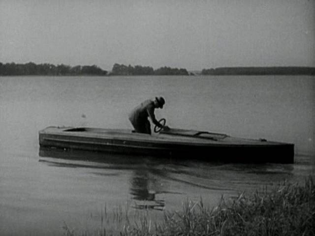 Na hladině startuje neznámý muž jednoduchý dřevěný člun, který má zachránit oba „plavce“. 